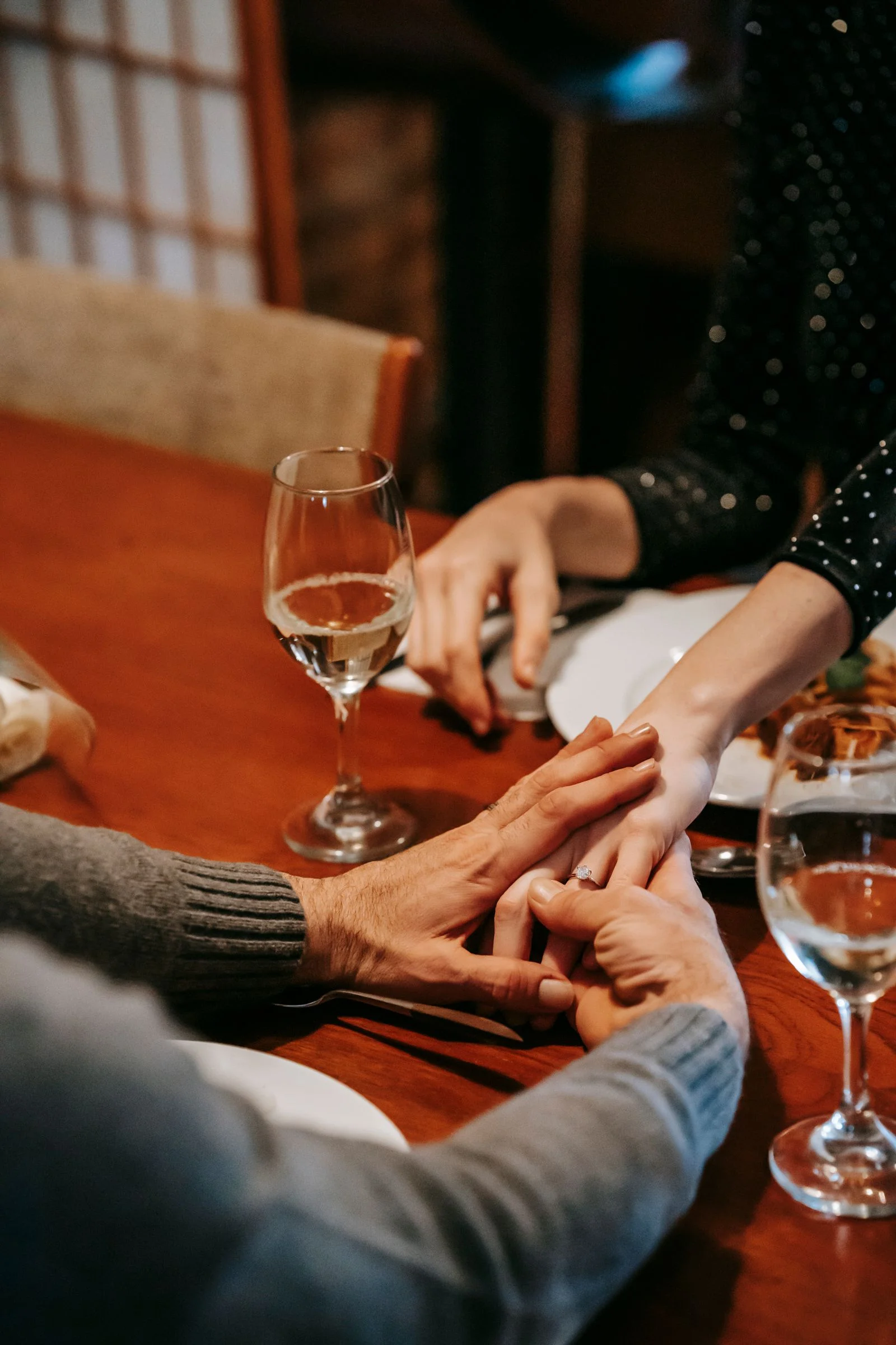 Dîner aux chandelles, mains entrelacées autour d'un verre de vin
